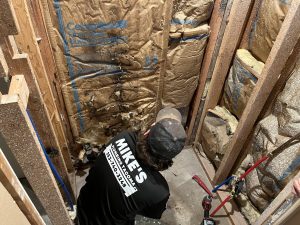Mikes Plumbing at work on pipework inside an opened wall