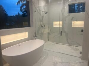 Bathroom remodel with marble walls, a freestanding tub and a glass shower