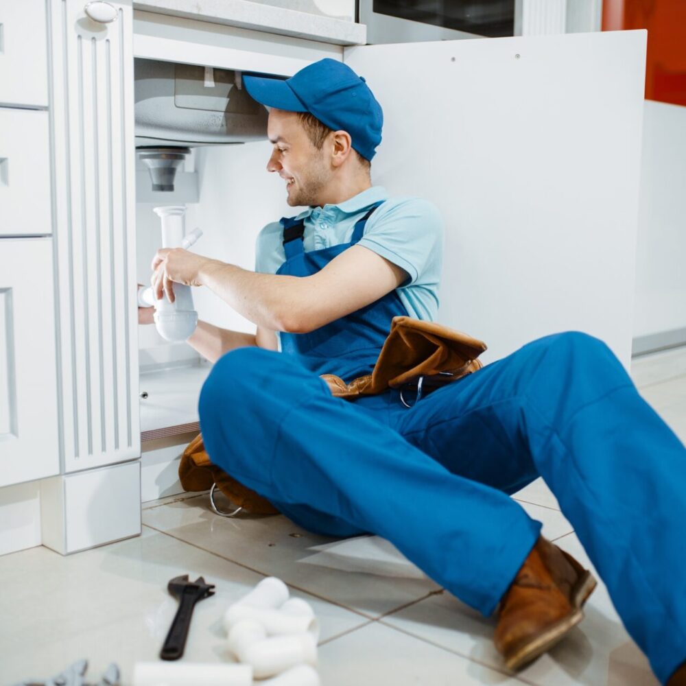 smiling-male-plumber-in-uniform-holds-drain-pipe-1