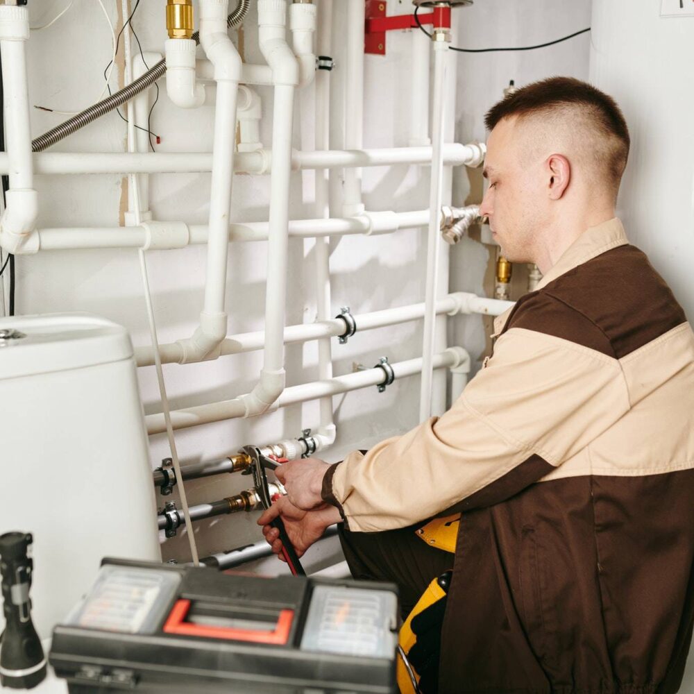 young-man-in-workwear-fixing-details-of-pipe